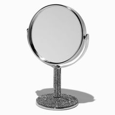 a round mirror sitting on top of a metal stand in front of a white background