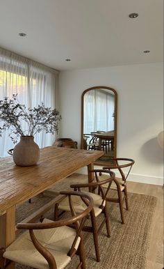 a wooden table with chairs and a vase on it