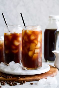 two glasses filled with iced coffee sitting on top of a table