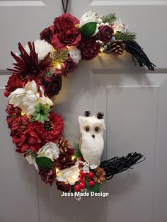 a wreath with an owl and flowers on it is hung on the front door, decorated with lights