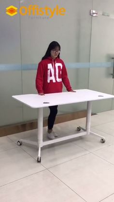 a woman in a red sweatshirt is standing at a white table