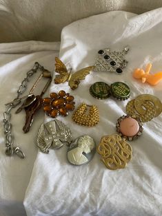 lot of 17 vintage junk drawer scrap items to make jewelry or crafts with.  lot includes 5 rusty keys hanging on a ring, plastic tiny baby, brass butterfly, gold plated horseshoe looking concho piece, flat silver plated cross angel wing concho, two rusty bottle caps,  hard plastic cameo, flat gold plated swirl with tarnishing and paint loss, topaz stoned brooch with broken hardware, scarf clip, big silver plated piece with rhinestones and black stones and a single pink earring spot on front Junk Drawer Jewelry, Vintage Charms For Crafting Jewelry, Pink Earring, Vintage Junk, Crafts Jewelry, Junk Drawer, Le Lot, Topaz Stone, Pink Earrings