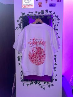 a white t - shirt hanging on a purple wall