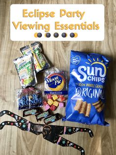 an assortment of snacks and candy on a wooden table with the words eclipse party viewing essentials