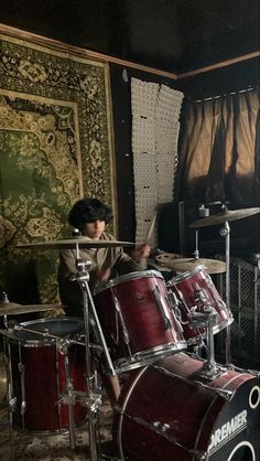 a young boy is playing drums in a room