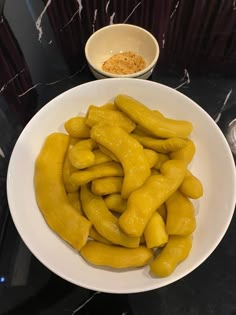 a white plate topped with yellow fruit next to a small bowl filled with seasoning