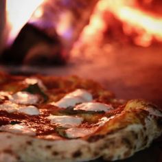 a pizza sitting on top of a table next to a fire