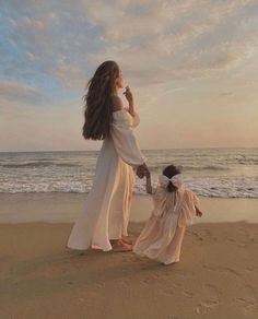 mother and daughter walking on the beach at sunset