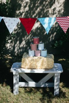 a picnic table with hay bales, cups and buntings on it in front of a wall