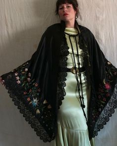 "Beautiful antique Victorian era black satin shawl with silk floral embroidery. Yellow tissue silk lining, two large braided tassel closures at the neckline, and a hook and eye closure below the bust. Black scalloped lace trim. The embroidery on this shawl is unreal and the colors are still extremely vibrant. There are even a few specs of pollen floating around! Measures 90\" x 46\". Condition: Great antique condition. Some fraying/snagging on embroidery, some lightened areas to black satin, and Luxury Black Embroidered Shawl, Elegant Luxury Shawl With Intricate Embroidery, Black Embroidered Silk Shawl, Black Silk Wedding Shawl, Black Bohemian Shawl For Spring, Black Shawl With Intricate Embroidery In Traditional Drape, Black Bohemian Shawl For Wedding, Traditional Evening Shawl With Drape, Traditional Silk Shawl For Evening