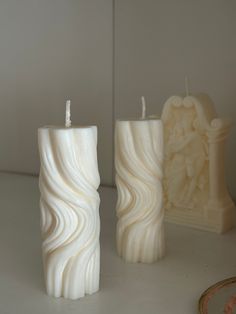 two white candles sitting next to each other on a table with a mirror in the background