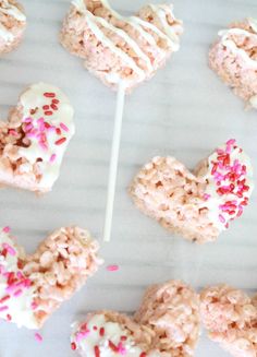 heart shaped lollipops with sprinkles and white frosting on a stick