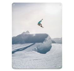 a man flying through the air while riding a snowboard down a snow covered slope