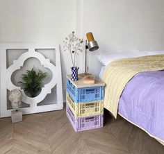 a bed room with a neatly made bed next to a night stand and a plant