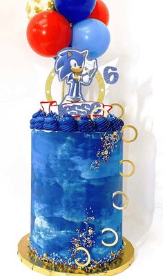 a blue cake topped with balloons and a sonic figure on it's top tier