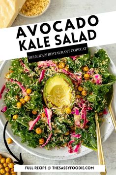 avocado kale salad on a white plate with gold spoons and garnishes