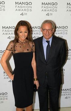 two people standing next to each other in front of a man and woman fashion awards