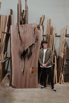 a man standing next to a large piece of wood that has been cut into pieces