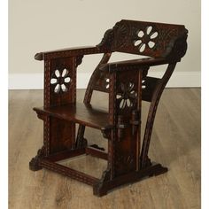 an old wooden chair with carved woodwork on the back and sides, sitting on a hard wood floor