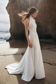 a woman standing on top of a beach next to the ocean wearing a white dress