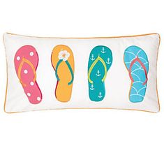 four pairs of flip flops on a white pillow with an orange border and blue, pink, green, yellow, and white trim