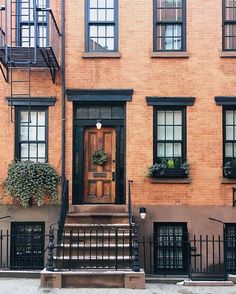 an apartment building with stairs leading up to the front door and windows on either side