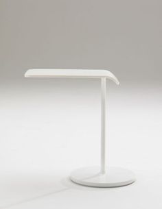 a white table with a curved top on a plain surface, in front of a gray background