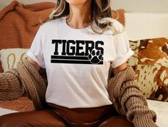 Tiger Shirt, Funny Tiger Lovers Gift, Tiger Paw Shirt, School Mascot Shirt, Tiger Face, Animal Prints, Tigers Spirit Shirt, Mascot Shirt 🟢 HOW TO ORDER 🟢 1. Check and Review ALL Photos 📷 2. Select Your T-Shirt Style, Size and T-Shirt Color from drop down menus ✨ 3.Select Your Design Print Color from images and mention in personalization section (Optional)🎨 4. Add to cart & place order 🛒 We're constantly striving to provide excellent service. We'd love to get your feedback :) 🚚📦 SHIPPING & Elementary School Spirit Shirts Tigers, Tiger Shirts Vinyl, Tiger Mascot Shirt Ideas, Tiger Tshirt Designs, Tiger Pride Shirts, Funny Tiger, Mascot Shirt, Tiger Paw, Tiger Shirt