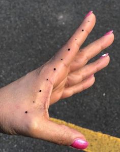 a woman's hand with black dots on it and pink nail polish holding out her palm