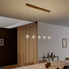 a dining room table with four lights hanging from the ceiling