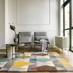 a living room with two chairs and a rug on the floor in front of a large window