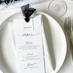 a white plate topped with a menu next to a wine glass and utensils