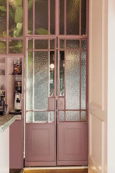 an open door leading into a kitchen with pink walls and cabinets on either side of it