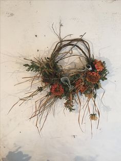 an arrangement of dried flowers and twigs on a white surface