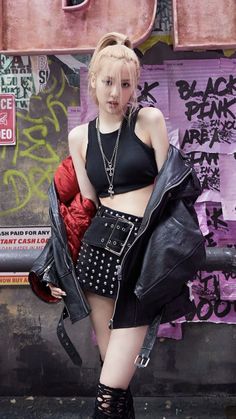 a young woman posing in front of a graffiti covered wall with her hand on her hip