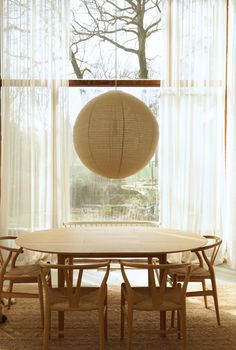 a round table with four chairs in front of a window and a hanging lantern above it