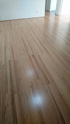 an empty room with hard wood flooring and white walls in the backround