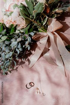 wedding rings and bouquet on pink background