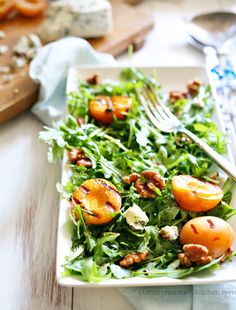 a white plate topped with lettuce and peaches on top of a wooden table