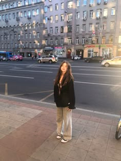 a woman standing on the sidewalk in front of some buildings