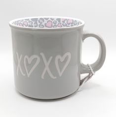 a grey coffee cup with hearts and xoxo written on the side, in front of a white background