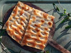 two pieces of flat bread sitting on top of a cutting board next to green leaves