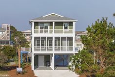 a white house surrounded by pine trees on the beach