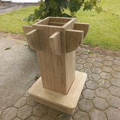 a wooden sculpture sitting on top of a stone floor next to a tree and grass