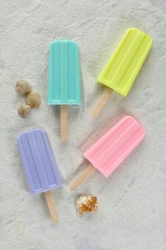 three popsicles with candy on them sitting next to some candies and marshmallows