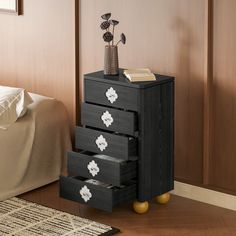 a black dresser with four drawers and flowers on top