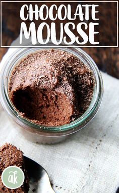 a glass jar filled with chocolate pudding sitting on top of a white napkin next to a spoon