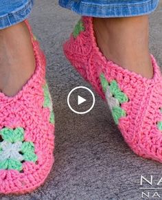 a woman's feet wearing pink crocheted slippers with green and white flowers