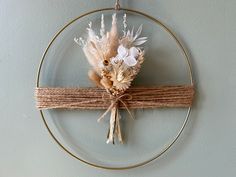 dried flowers are tied to a wire on a circular wall hanging ornament with twine and burlap