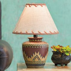 a lamp sitting on top of a table next to a potted plant